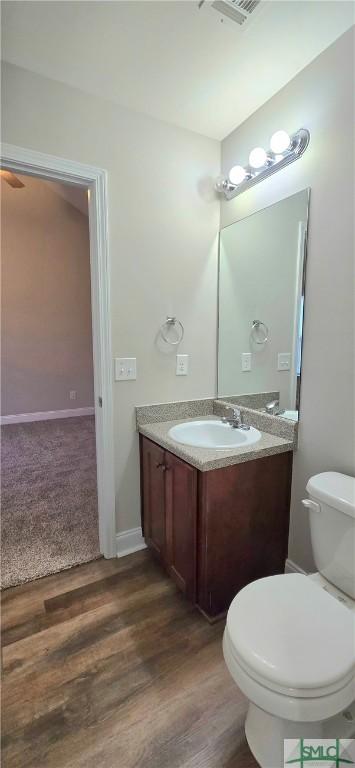 bathroom with hardwood / wood-style flooring, vanity, and toilet