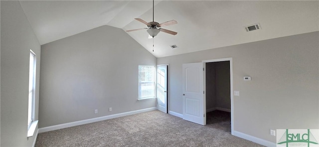 unfurnished bedroom with ceiling fan, a walk in closet, light colored carpet, and lofted ceiling