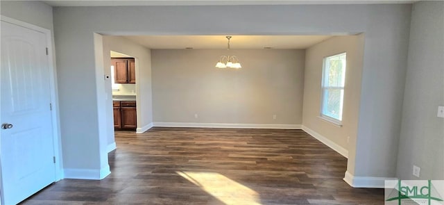 spare room featuring a chandelier and dark hardwood / wood-style floors