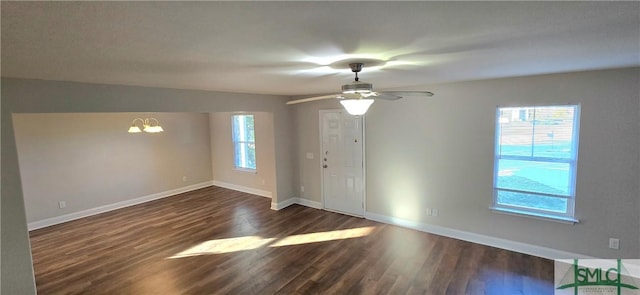 spare room with ceiling fan with notable chandelier, dark hardwood / wood-style flooring, and a wealth of natural light