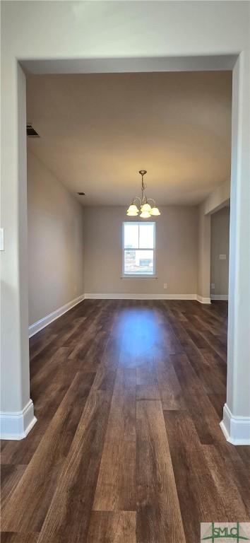 unfurnished dining area with dark hardwood / wood-style flooring and a notable chandelier