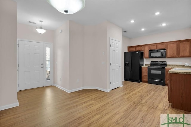 kitchen with sink, light wood-type flooring, hanging light fixtures, and black appliances