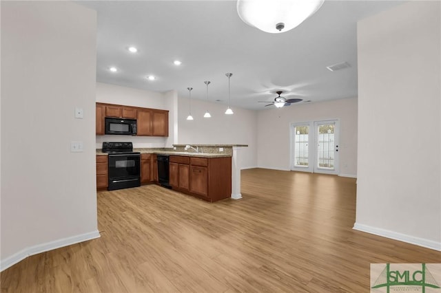 kitchen with sink, black appliances, decorative light fixtures, kitchen peninsula, and light wood-type flooring