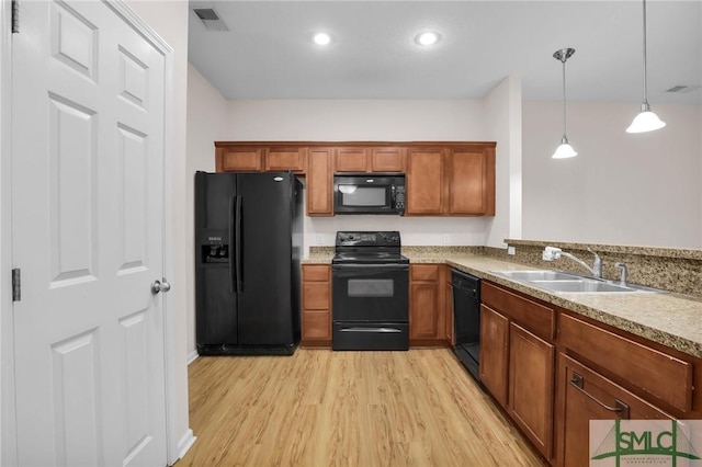 kitchen featuring light hardwood / wood-style floors, hanging light fixtures, black appliances, and sink