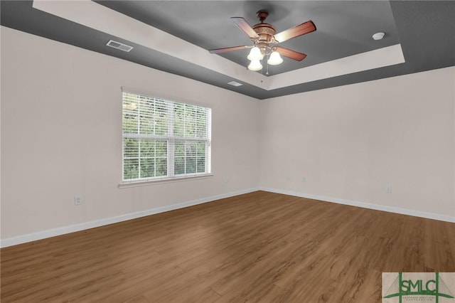 unfurnished room featuring hardwood / wood-style floors, a tray ceiling, and ceiling fan