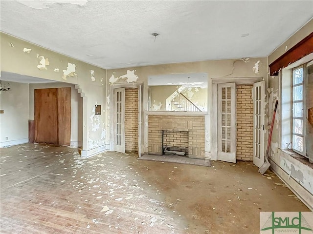 unfurnished living room with a brick fireplace, a textured ceiling, and a healthy amount of sunlight