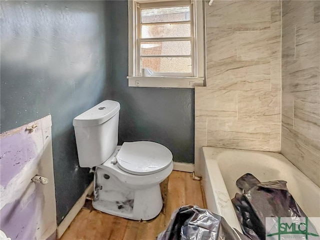 bathroom featuring toilet, hardwood / wood-style flooring, and a tub