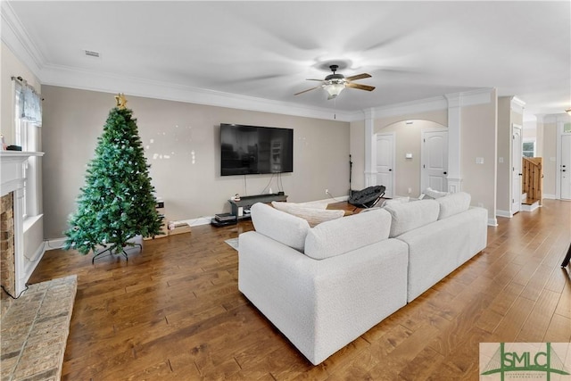 living room with ceiling fan, a fireplace, dark wood-type flooring, and ornamental molding