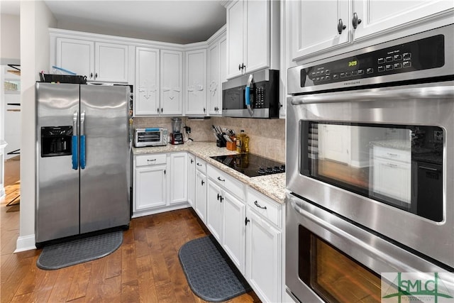 kitchen featuring light stone countertops, white cabinetry, dark wood-type flooring, and appliances with stainless steel finishes