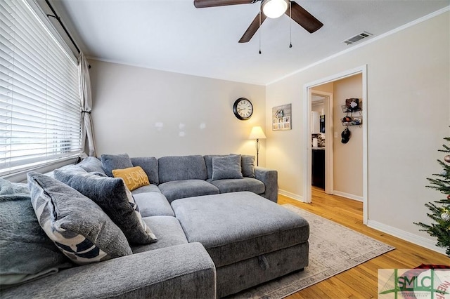 living room with wood-type flooring, ceiling fan, and ornamental molding