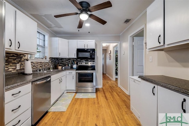 kitchen featuring light wood-type flooring, ornamental molding, appliances with stainless steel finishes, tasteful backsplash, and white cabinetry