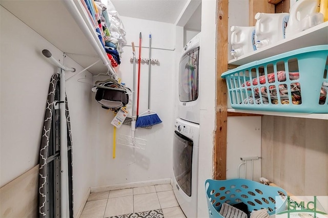 clothes washing area with light tile patterned floors and stacked washer and dryer