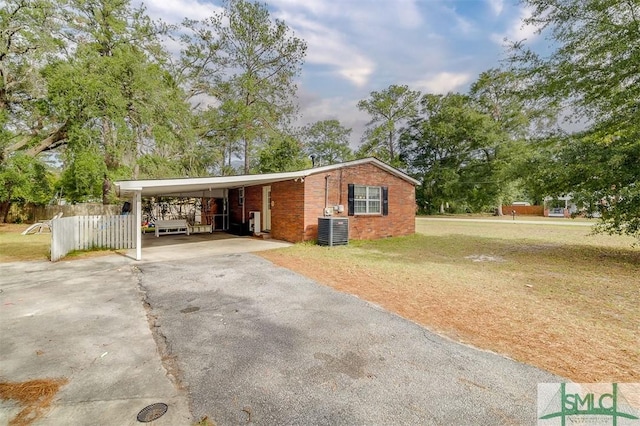 view of front of home featuring a carport, central air condition unit, and a front lawn