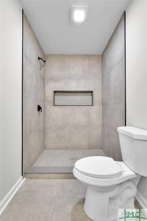 bathroom with tiled shower, tile patterned flooring, and toilet