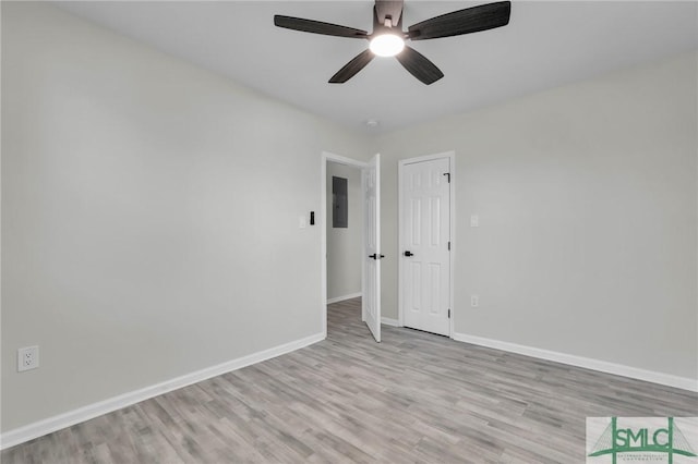 unfurnished room with electric panel, ceiling fan, and light hardwood / wood-style floors