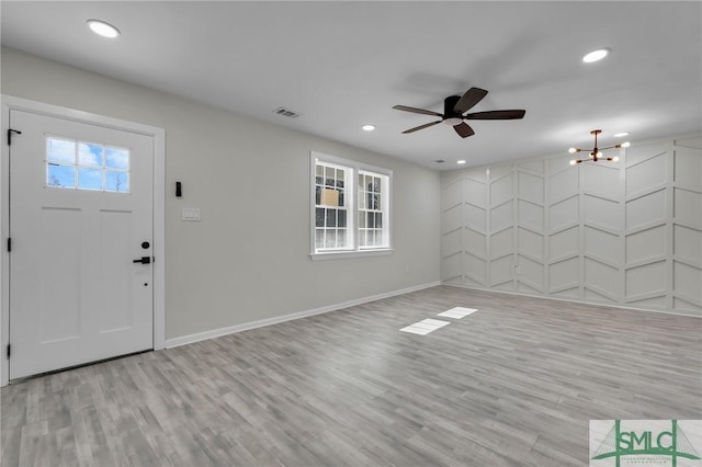 foyer featuring ceiling fan with notable chandelier and light wood-type flooring