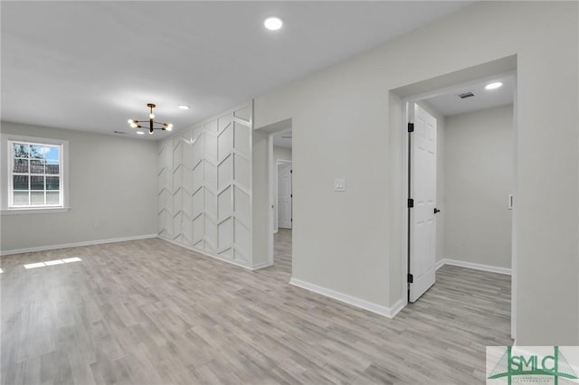 unfurnished room featuring light wood-type flooring and an inviting chandelier