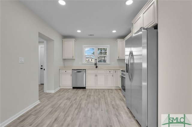 kitchen with light hardwood / wood-style flooring, white cabinets, and stainless steel appliances