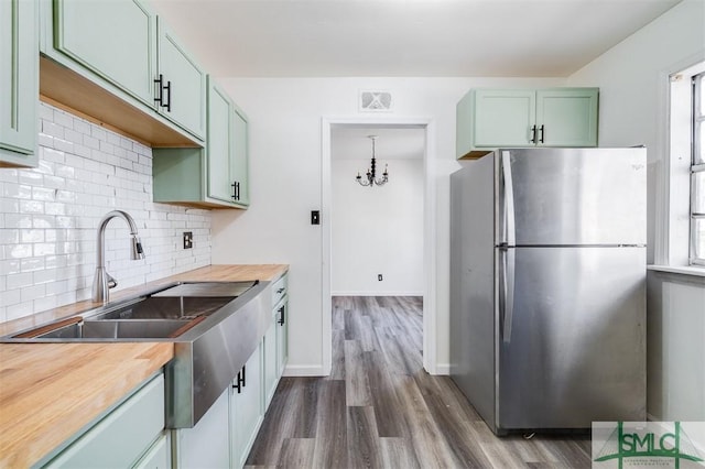 kitchen featuring stainless steel refrigerator, dark hardwood / wood-style flooring, wooden counters, pendant lighting, and green cabinetry