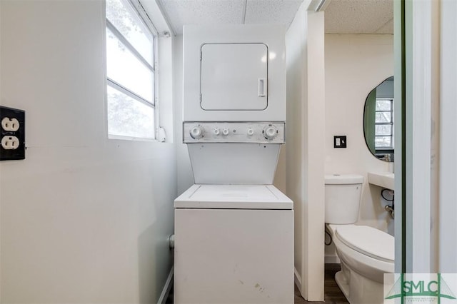 bathroom with hardwood / wood-style flooring, toilet, stacked washer and dryer, and a wealth of natural light