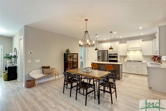 dining area featuring light hardwood / wood-style floors, sink, and an inviting chandelier