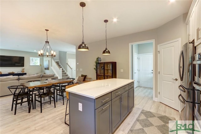 kitchen with pendant lighting, a center island, light hardwood / wood-style flooring, stainless steel fridge, and white cabinetry