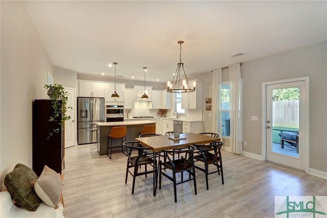 dining area featuring light hardwood / wood-style flooring, plenty of natural light, a notable chandelier, and sink