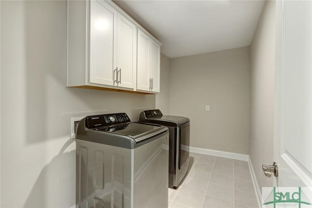 laundry room featuring washing machine and clothes dryer, light tile patterned flooring, and cabinets