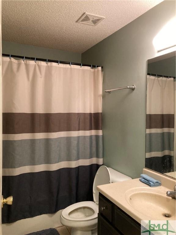 bathroom featuring vanity, a textured ceiling, and toilet