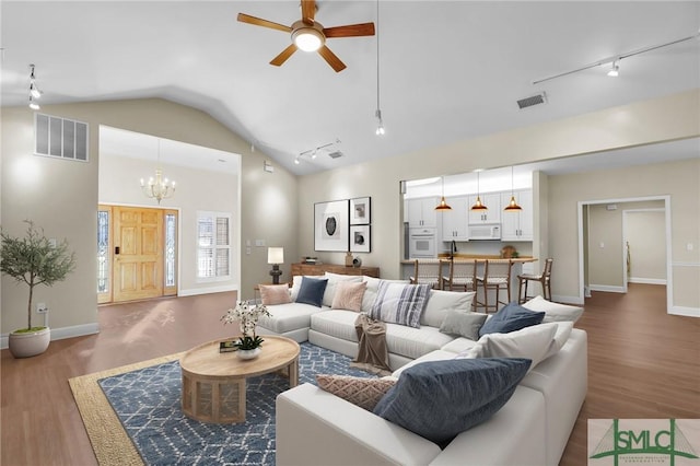 living room featuring ceiling fan with notable chandelier, vaulted ceiling, track lighting, and wood-type flooring