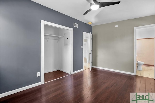 unfurnished bedroom featuring ceiling fan, dark wood-type flooring, connected bathroom, and a closet