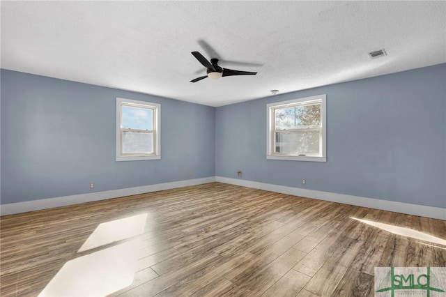 empty room featuring hardwood / wood-style flooring, plenty of natural light, and a textured ceiling