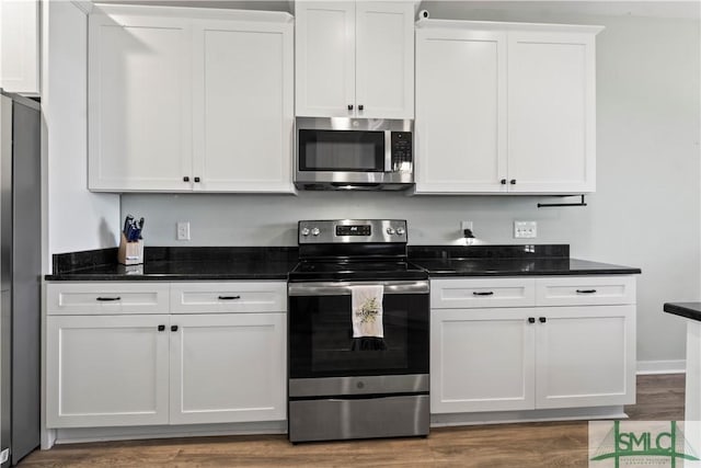 kitchen featuring dark stone countertops, white cabinetry, dark wood-type flooring, and stainless steel appliances