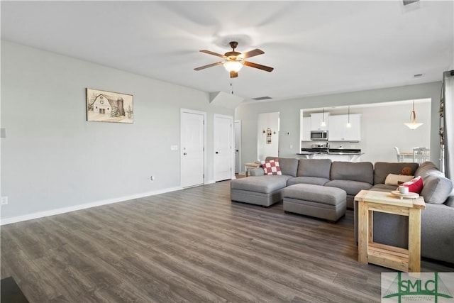 living room with ceiling fan and dark hardwood / wood-style flooring