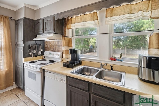 kitchen with dark brown cabinetry, sink, backsplash, white appliances, and light tile patterned flooring