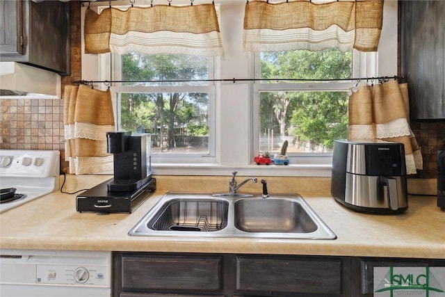 kitchen with dark brown cabinetry, white dishwasher, backsplash, and sink