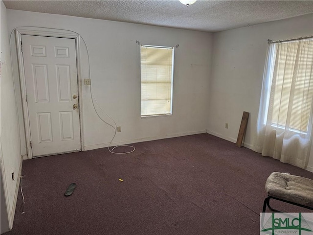 unfurnished room with dark carpet and a textured ceiling