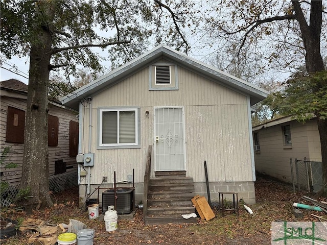 bungalow-style house with entry steps, central AC, and fence