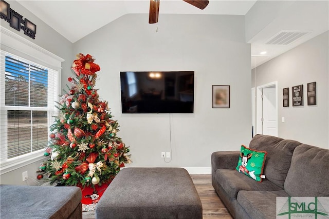 living room with a wealth of natural light, hardwood / wood-style floors, ceiling fan, and vaulted ceiling