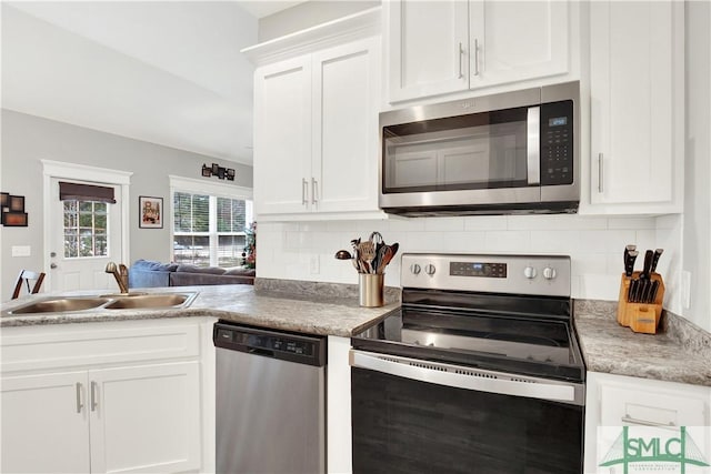 kitchen with tasteful backsplash, white cabinetry, sink, and stainless steel appliances