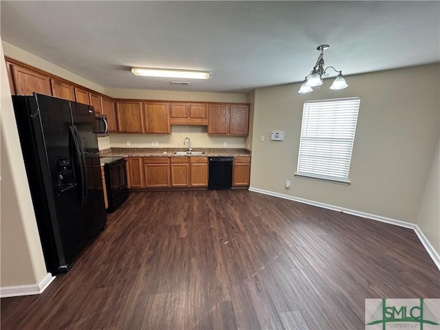 kitchen with dark wood-type flooring, sink, black appliances, decorative light fixtures, and an inviting chandelier