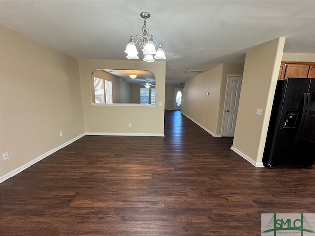 empty room with ceiling fan with notable chandelier and dark hardwood / wood-style floors