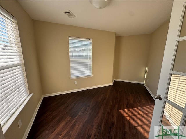 empty room with dark hardwood / wood-style floors and a wealth of natural light