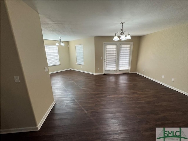 unfurnished room with dark hardwood / wood-style floors and an inviting chandelier