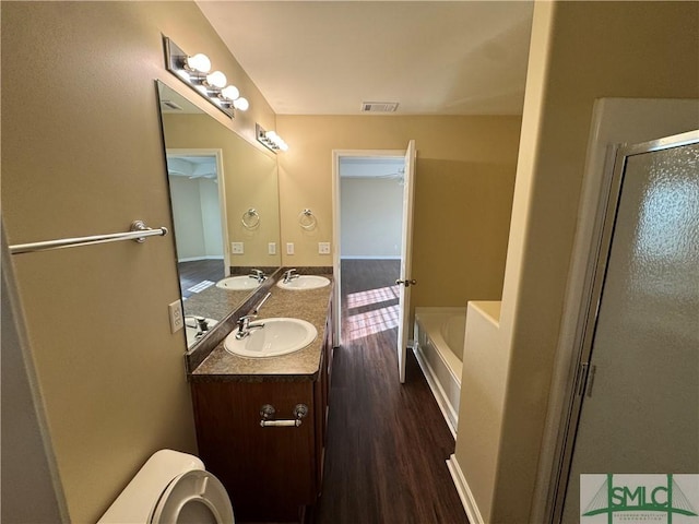 full bathroom featuring hardwood / wood-style floors, vanity, separate shower and tub, and toilet