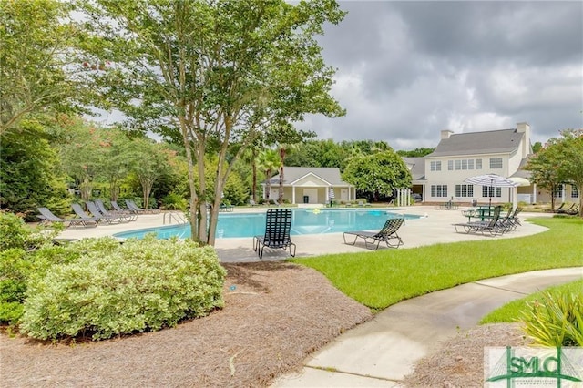 pool with a patio and a lawn