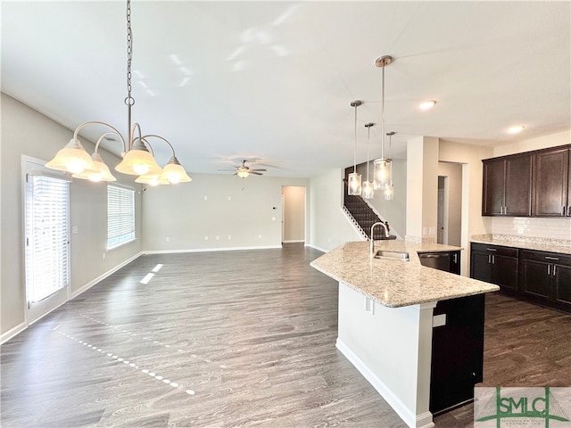 kitchen featuring dark wood-type flooring, pendant lighting, a sink, dark brown cabinetry, and baseboards