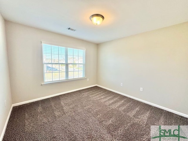 unfurnished room with baseboards, visible vents, and dark carpet