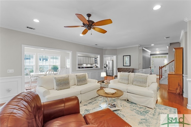 living room featuring light hardwood / wood-style floors, ceiling fan, and crown molding