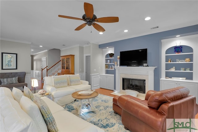 living room with built in shelves, crown molding, and a high end fireplace